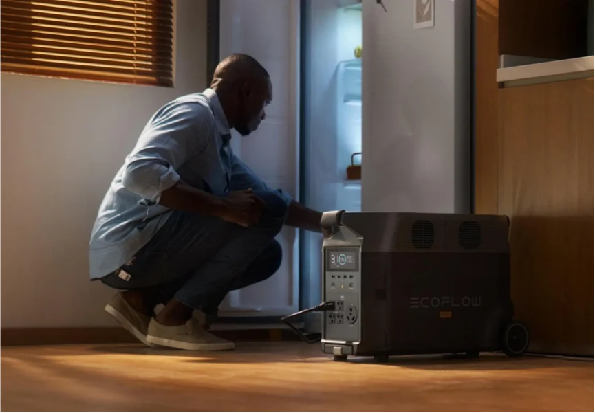 A man using the EcoFlow DELTA Pro portable power station to keep a refrigerator running during a home power outage, showcasing reliable backup power for essential household appliances