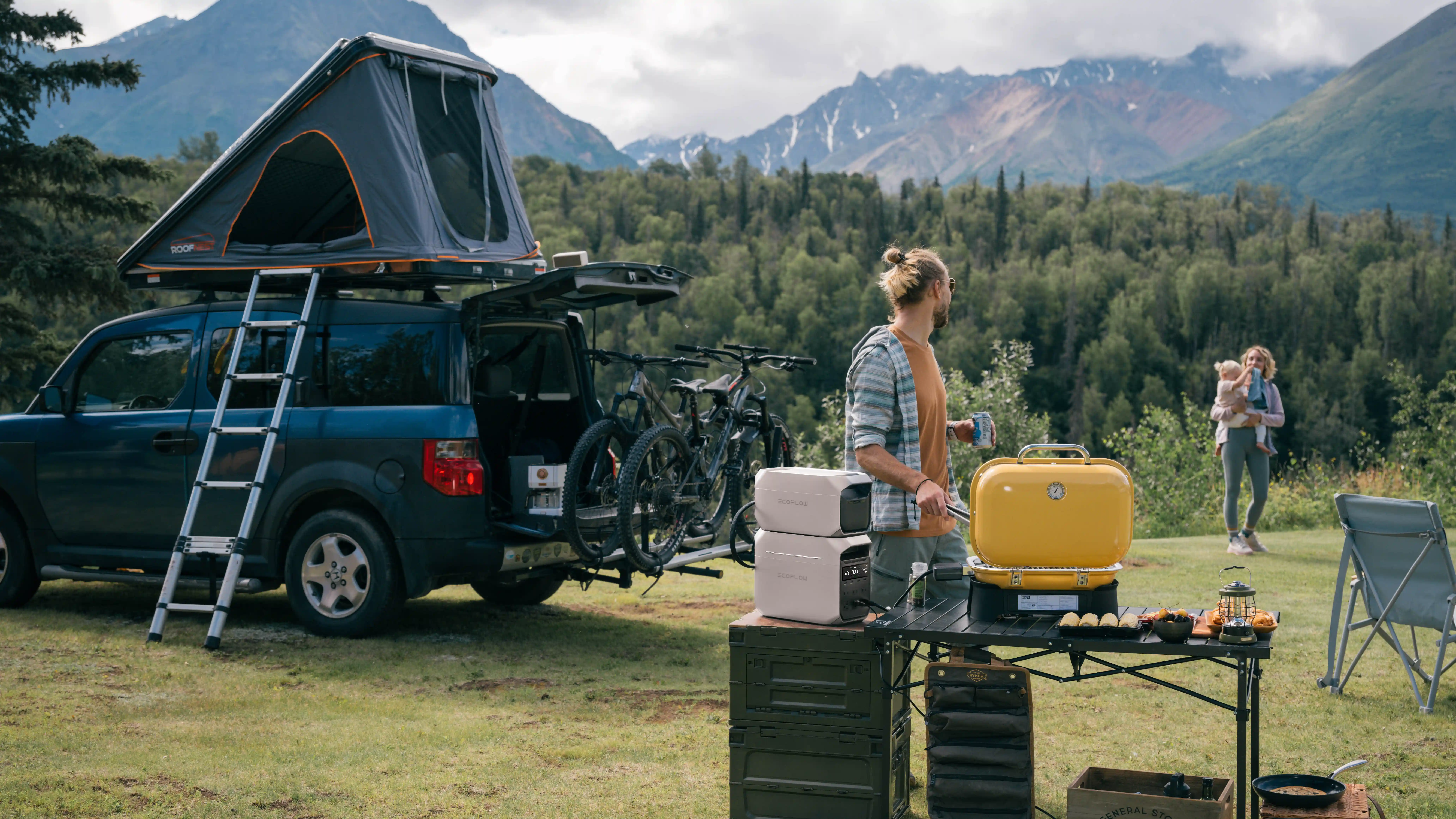 Family camping setup with EcoFlow DELTA 3 Plus portable power station powering a portable grill and outdoor cooking gear at a forested mountain campsite