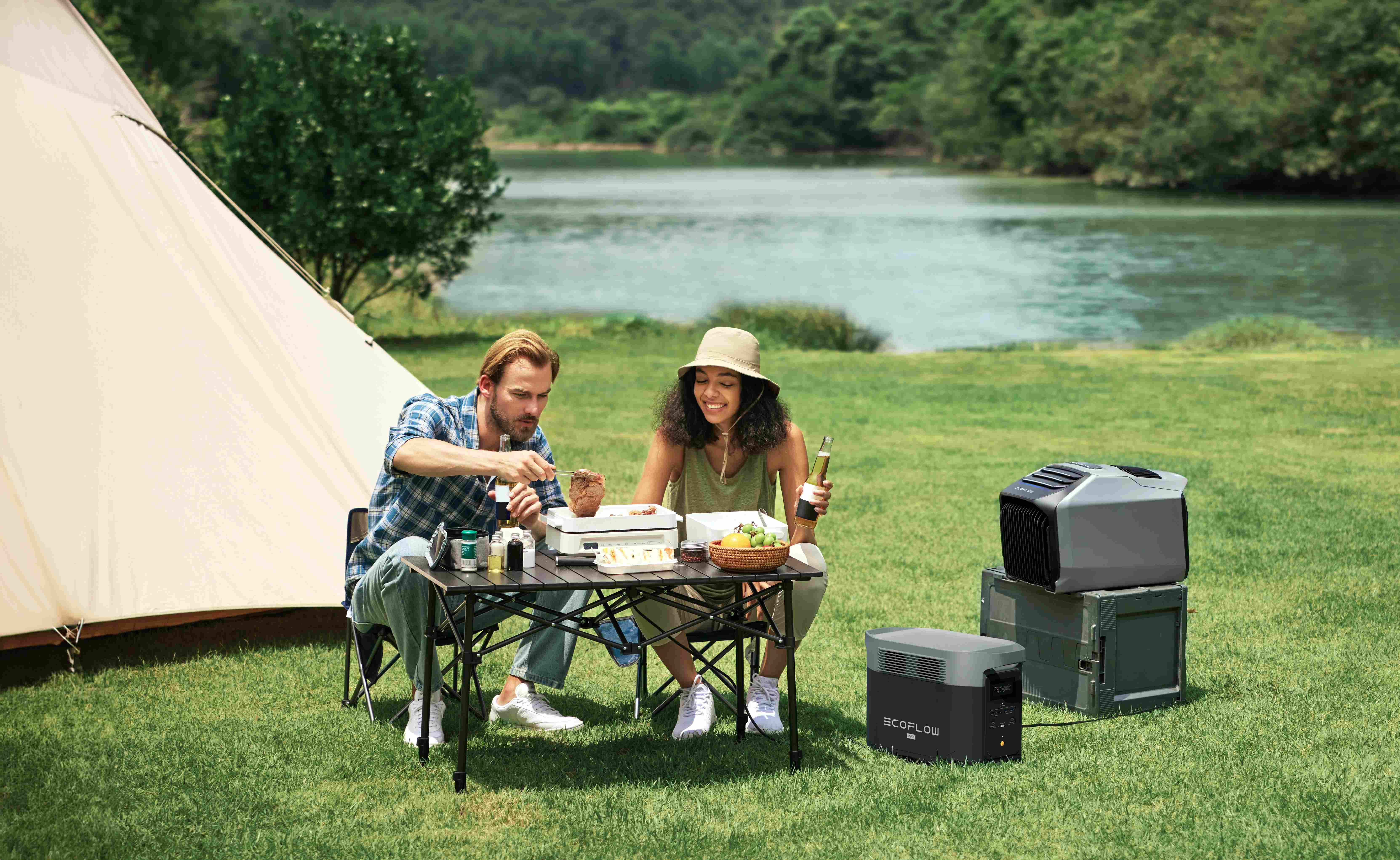 EcoFlow Delta 2 Max powering a portable grill and cooler for a couple enjoying a lakeside camping picnic.