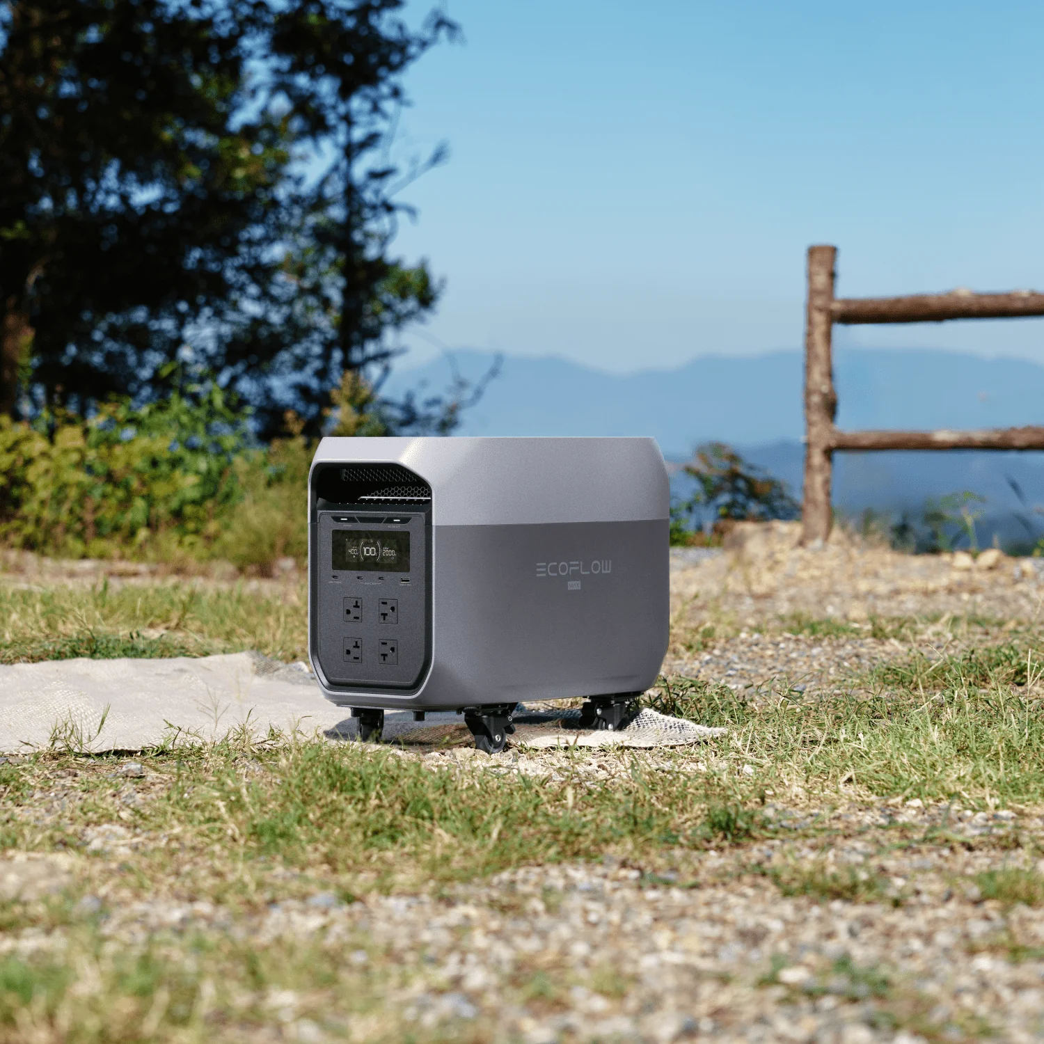 EcoFlow Delta 3 Max Plus portable power station with wheels, set outdoors against a scenic mountain campsite backdrop.