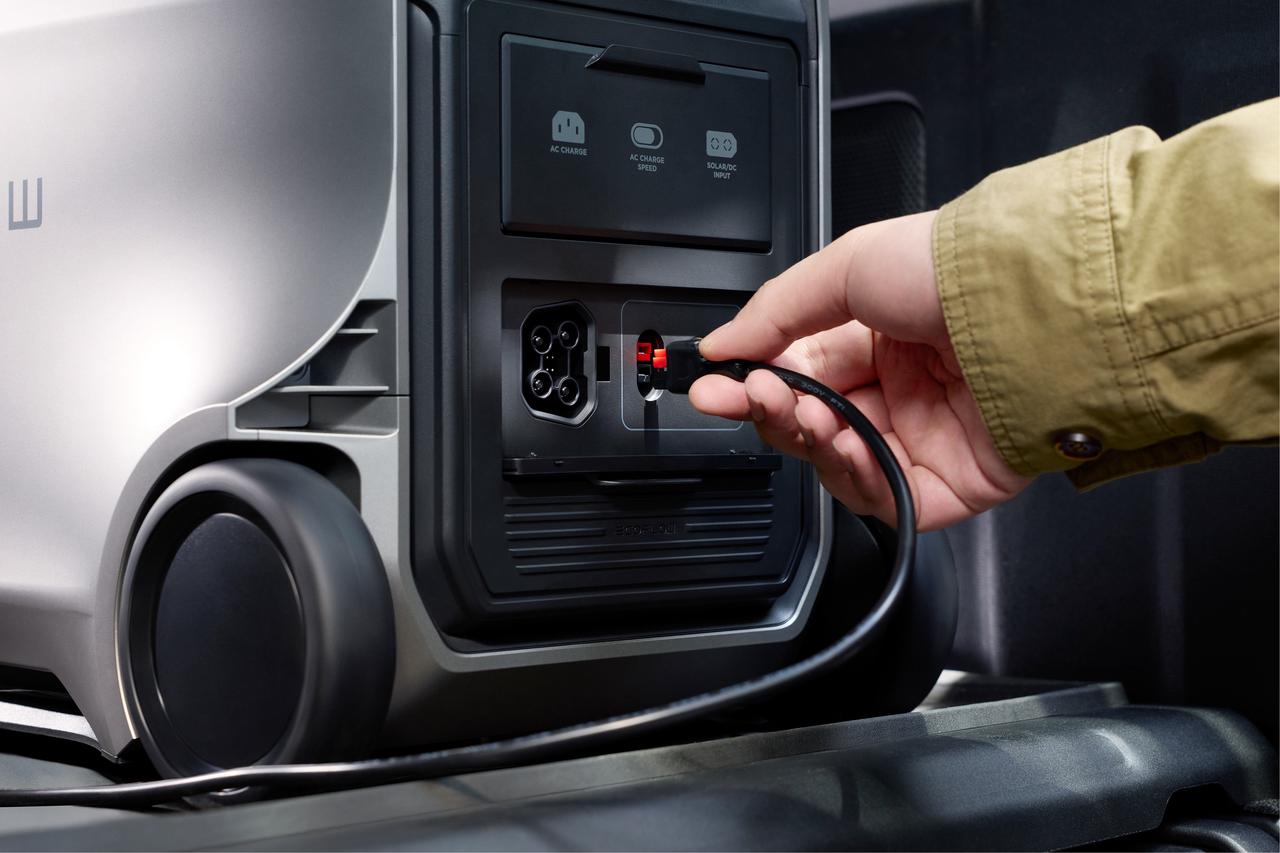Close-up shot of hand plugging charging cable into EcoFlow DELTA 3 Ultra multi input port panel, showcasing AC, solar and car charging interfaces with built-in rolling wheels