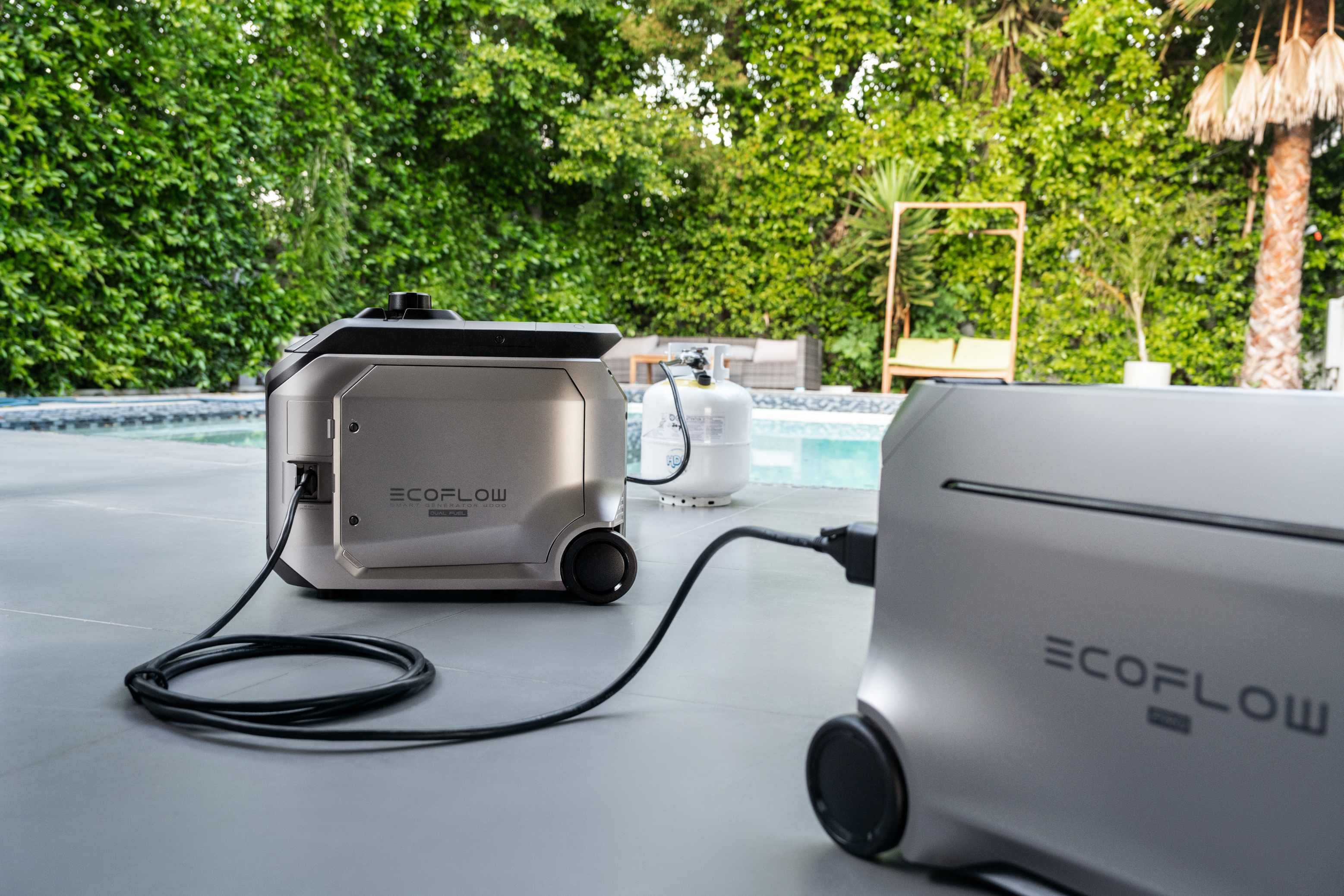 Two connected EcoFlow DELTA Pro 3 portable power stations beside backyard swimming pool, EcoFlow propane gas generator charging unit, expandable outdoor home backup power system close-up